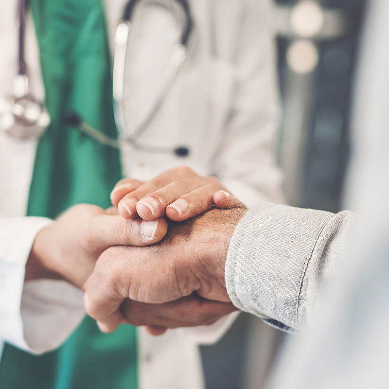 close-up of patient's hand held by provider's both hands