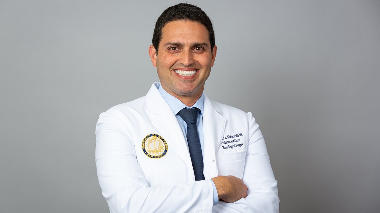 Alexander Khalessi, MD, MBA, in white coat, arms folded